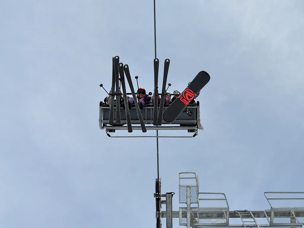 Blick von unten auf einen Sessellift mit Skiern gegen den Himmel.